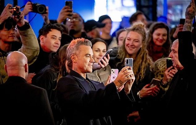 Хитмейкер взъерошил свои короткие седеющие волосы, позируя для фотографий перед показом