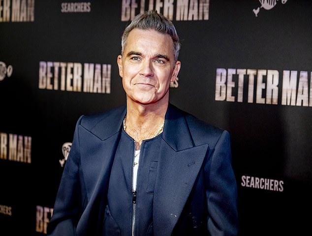 Исполнитель «Let Me Entertain You» выбрал белую рубашку под темно-синим костюмом и надел два золотых ожерелья