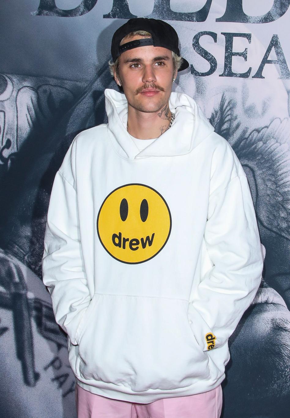 Джастин Бибер в белой футболке Drew House на улице.