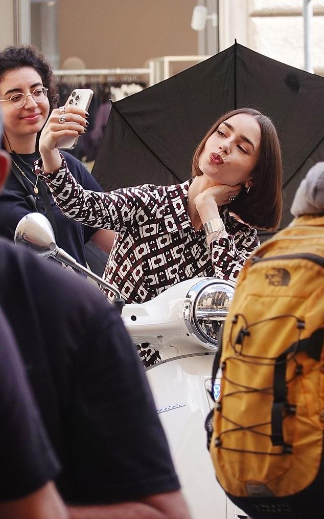 Эмили мило позировала для фото, сидя на своем кремовом мотороллере Vespa.