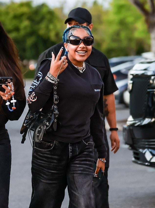 Образ 11-летнего "непо-бейби": черная футболка Chrome Hearts с длинным рукавом, широкие джинсы в тон, сумка и кроссовки.