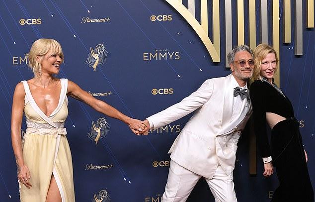 Рита Ора игриво оказалась «третьим лишним» на красной дорожке премии «Эмми» в Лос-Анджелесе в воскресенье вечером, куда она пришла со своим мужем, Тайкой Вайтити
