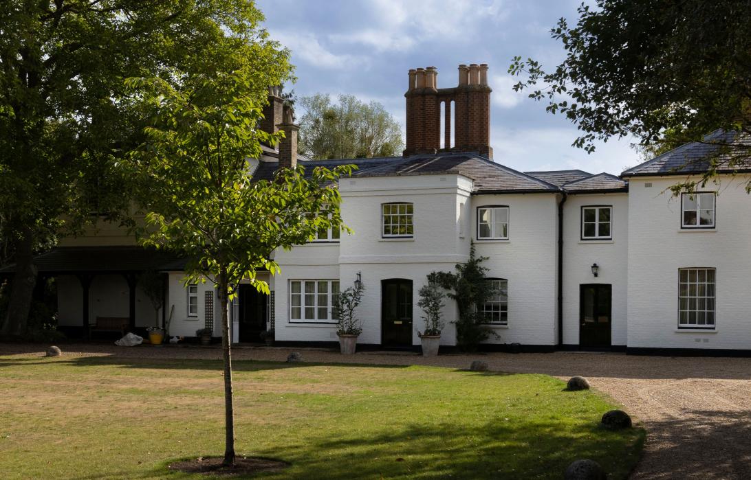 Фрогмор-коттедж – белый дом с многочисленными чернорамными окнами, темно-серой крышей и высокими кирпичными трубами.