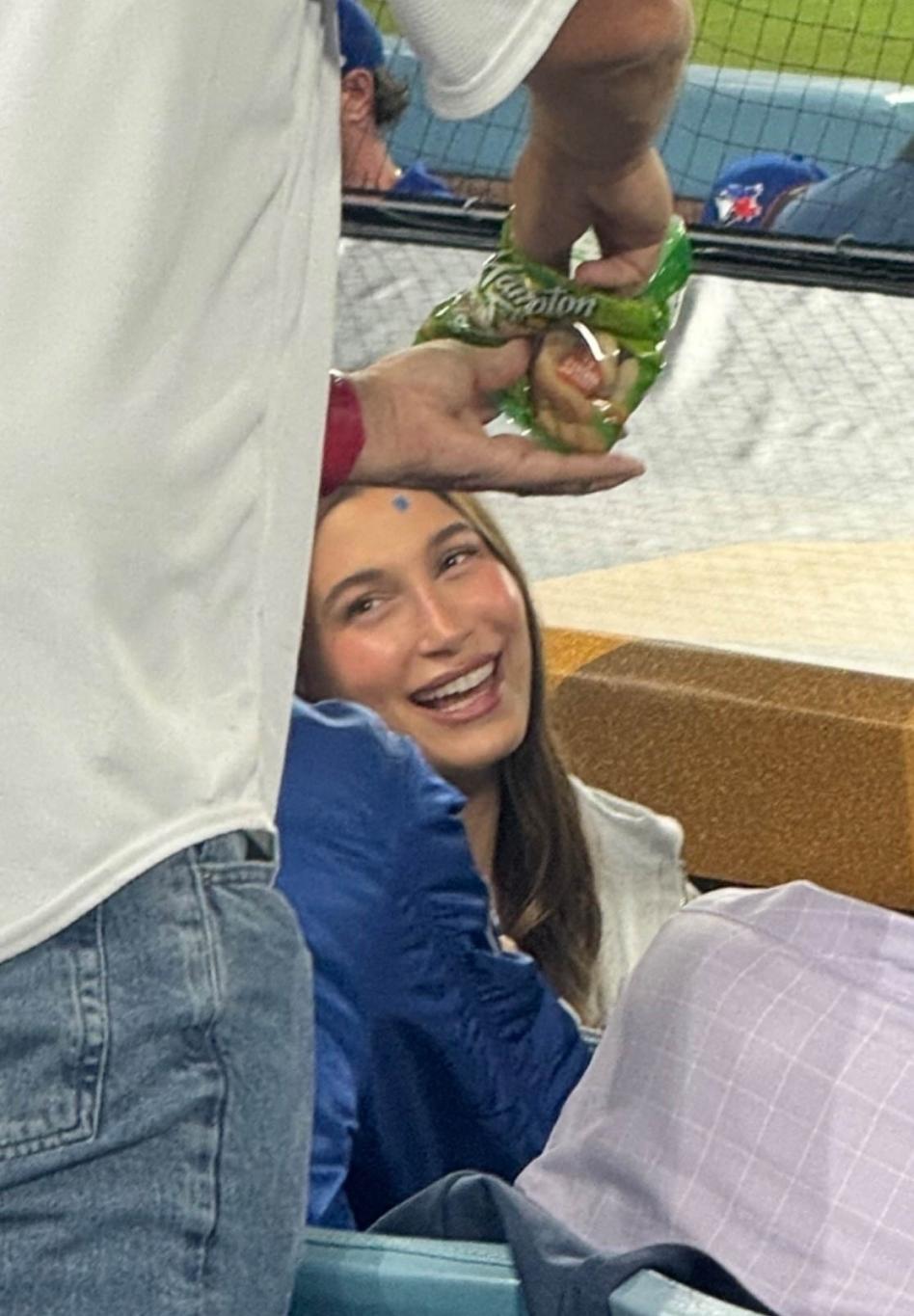 Улыбающаяся Хейли Бибер на бейсбольном матче.