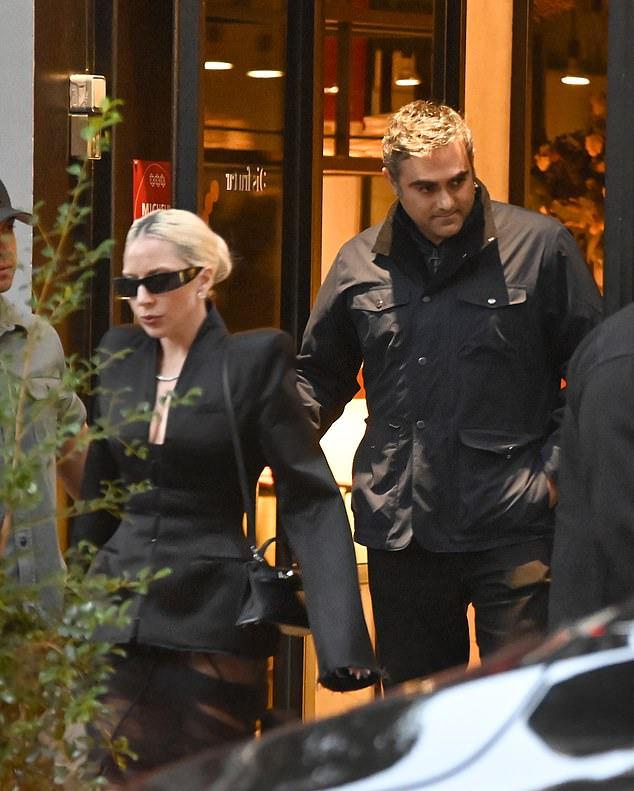 Строгий образ: платиновые волосы, собранные в тугой шиньон, и модные прямоугольные очки на лице.