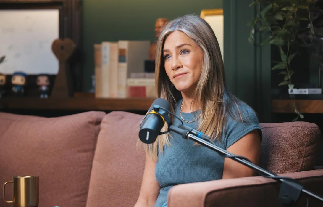 Дженнифер Энистон выступает с микрофоном.