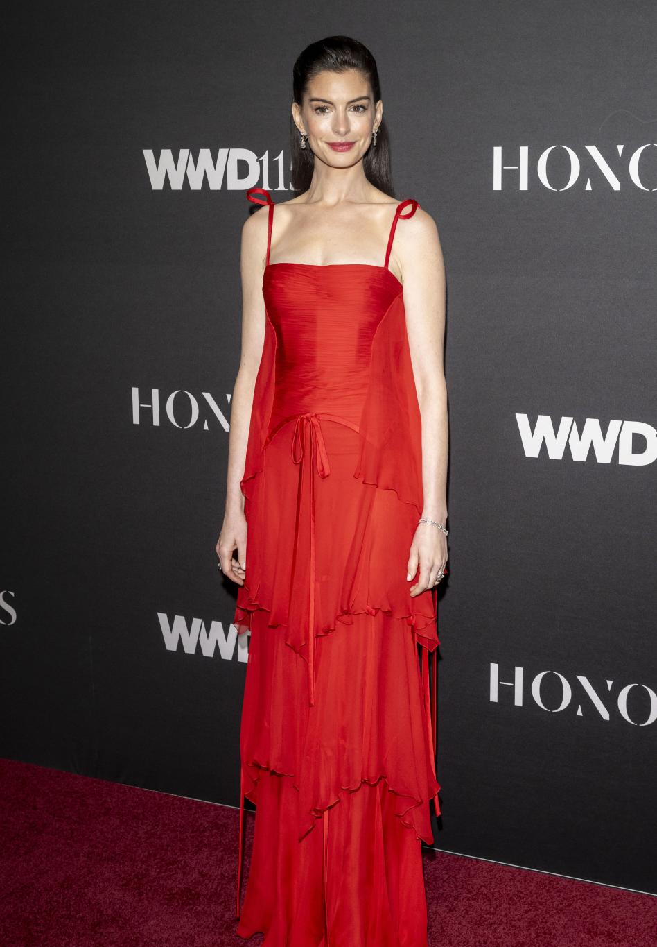 Энн Хэтэуэй в красном ярусном платье на церемонии WWD Honors 2025.