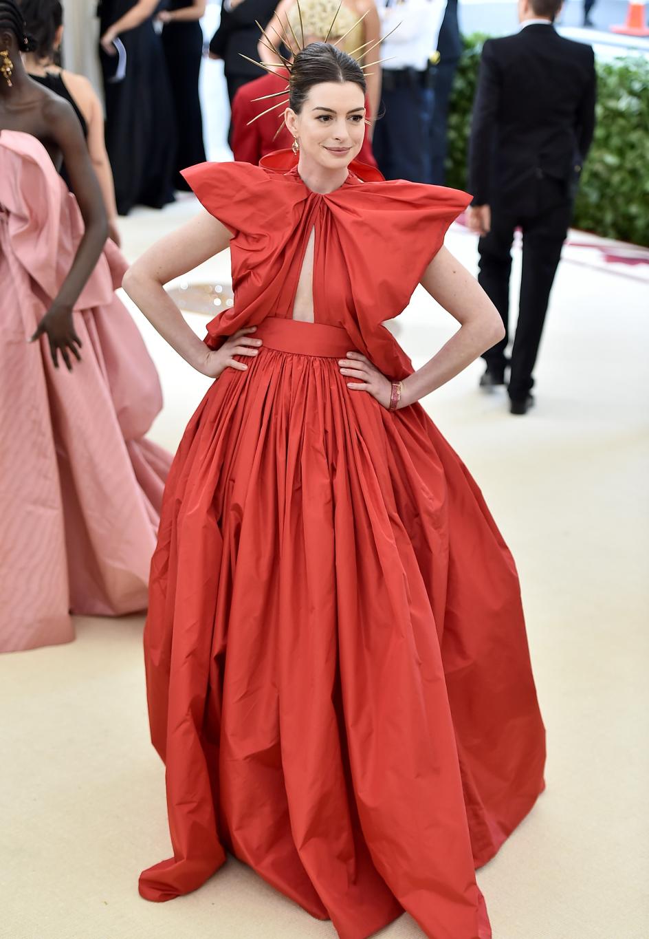 Энн Хэтэуэй на Met Gala в алом вечернем платье и эффектном золотом остроконечном головном уборе.