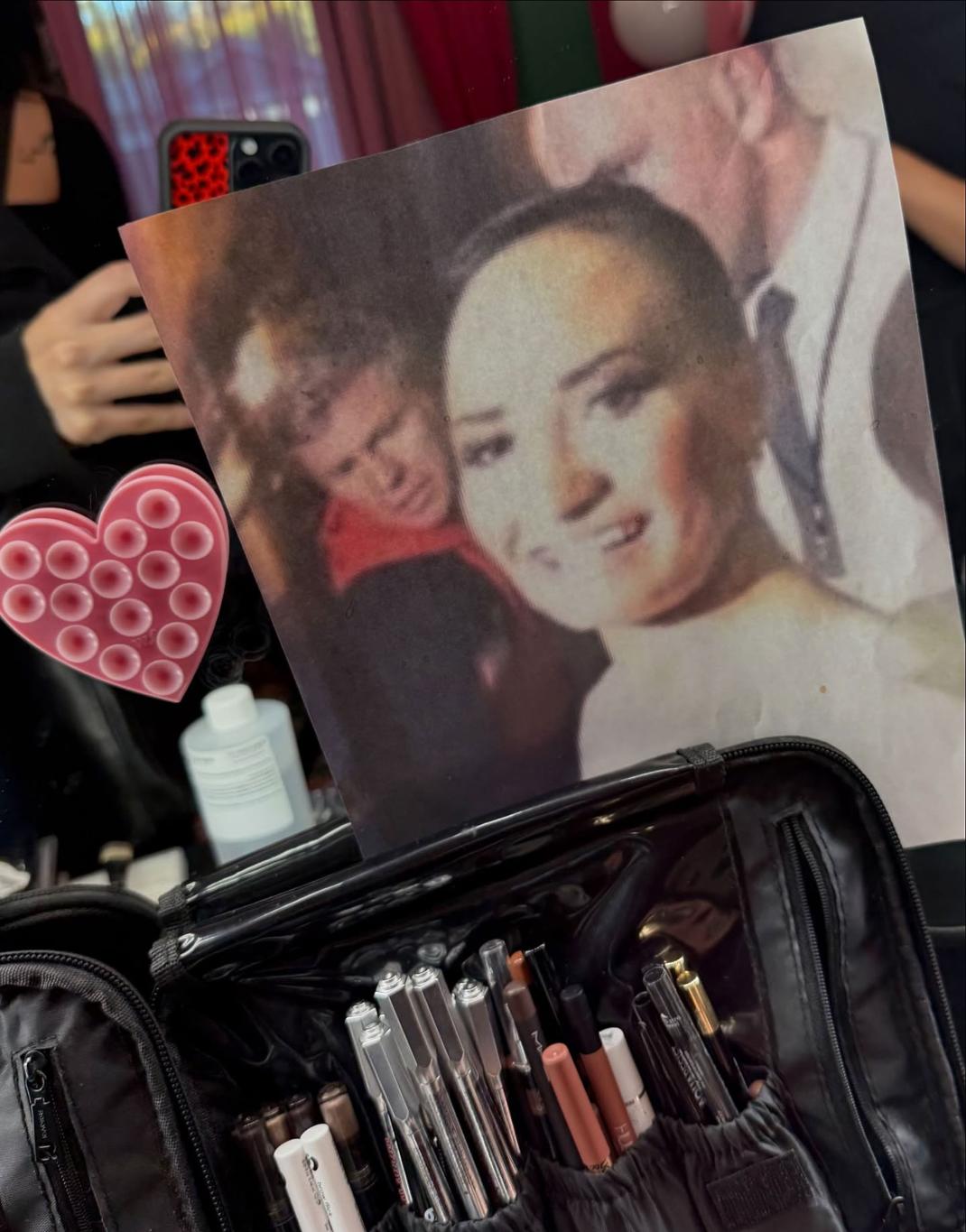 Деми Ловато демонстрирует распечатку мема Пут Ловато над косметичкой.