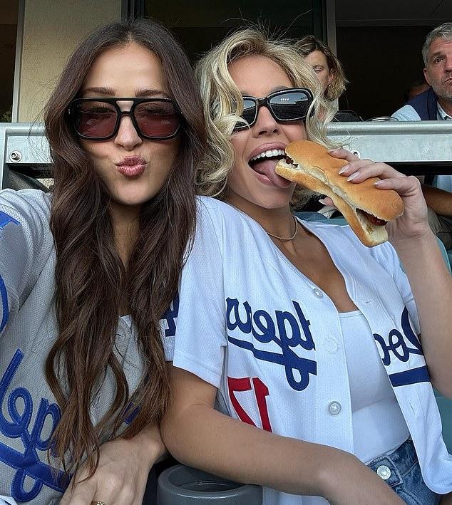 В толпе она надкусила хот-дог, приняла пикантную позу и съела его с бывшей коллегой по «Immaculate» Кейли МакГрегор.