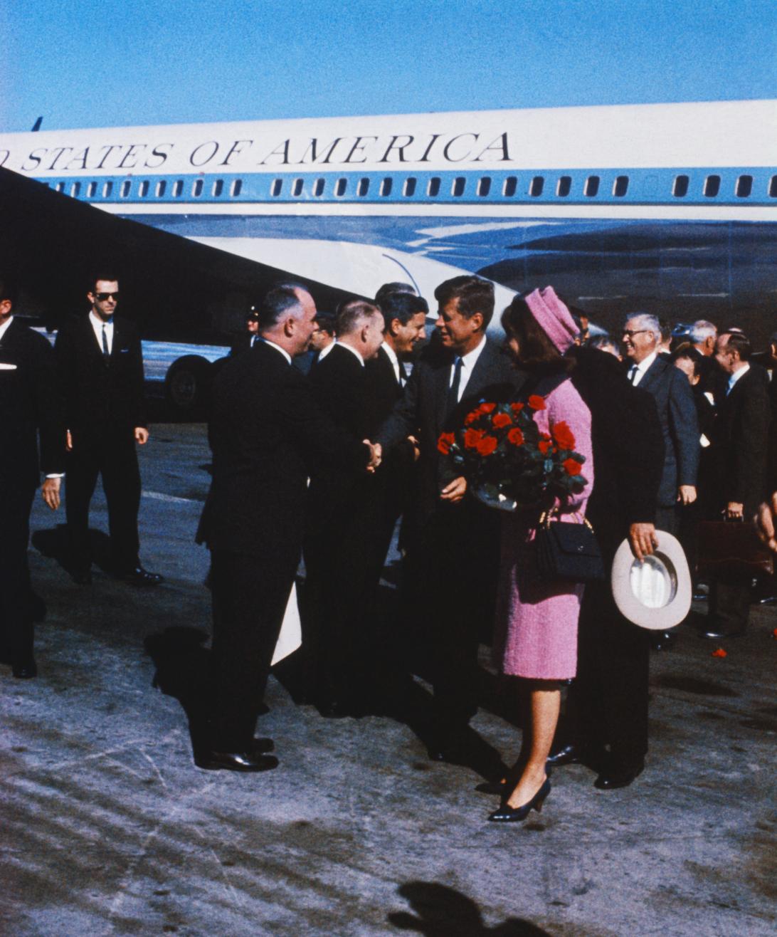 Чета Кеннеди спускается с борта №1, приветствуя официальных лиц на церемонии встречи в Далласе.