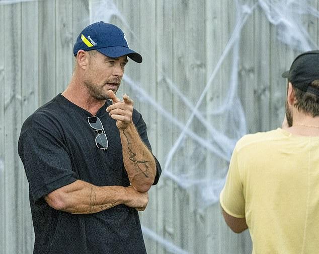 Крис выбрал расслабленный стиль: свободная черная футболка, бейсболка и солнцезащитные очки, заткнутые за воротник.