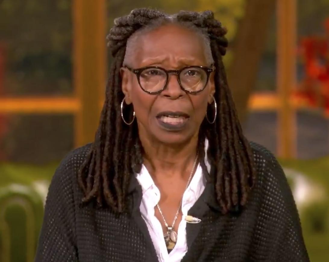 Вупи Голдберг в очках, в чёрной рубашке поверх белой воротничковой, с колье, серьёзно говорит.