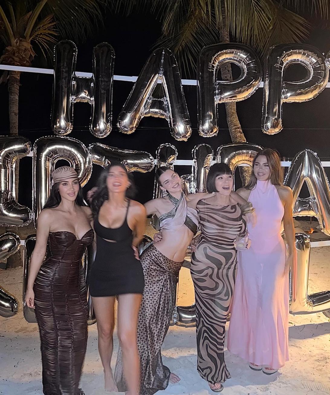 Человек с поднятыми руками стоит у воды, пока фейерверки расцветают в ночном небе.