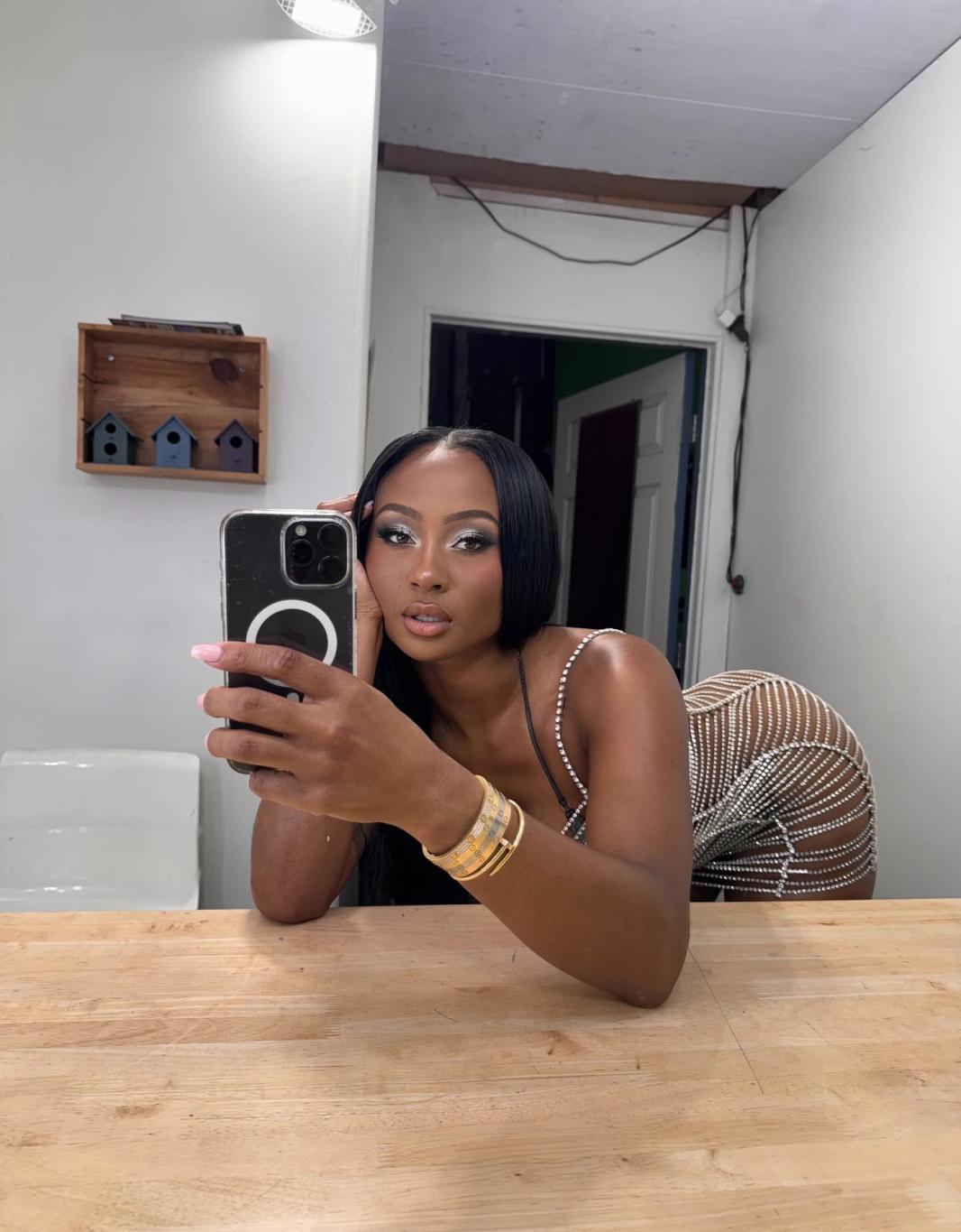 Кейла Николь позирует для зеркального селфи, демонстрируя свою фигуру в мерцающем облегающем платье.