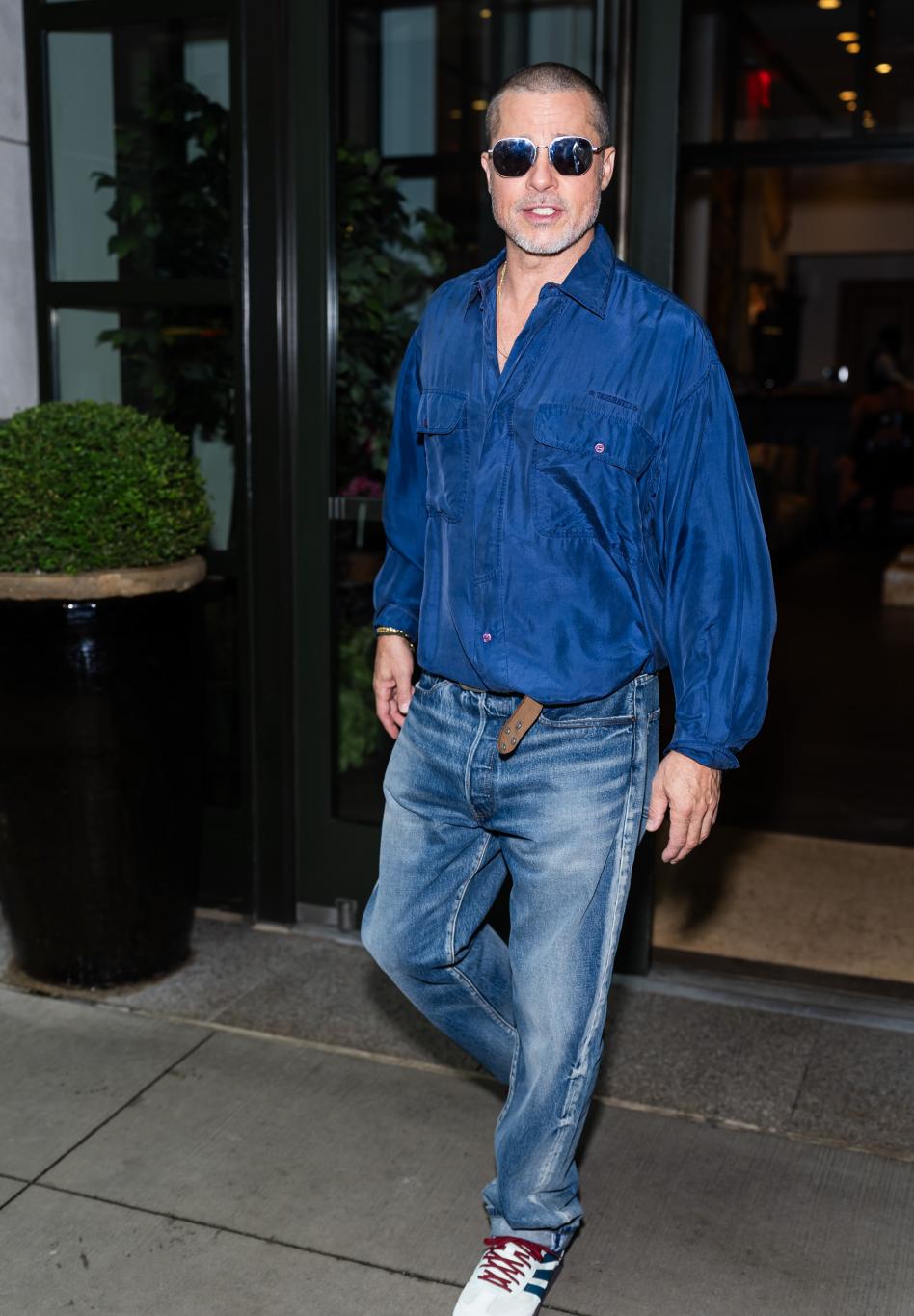 На улице Нью-Йорка Брэд Питт прогуливается в синей рубашке, джинсах и солнечных очках.