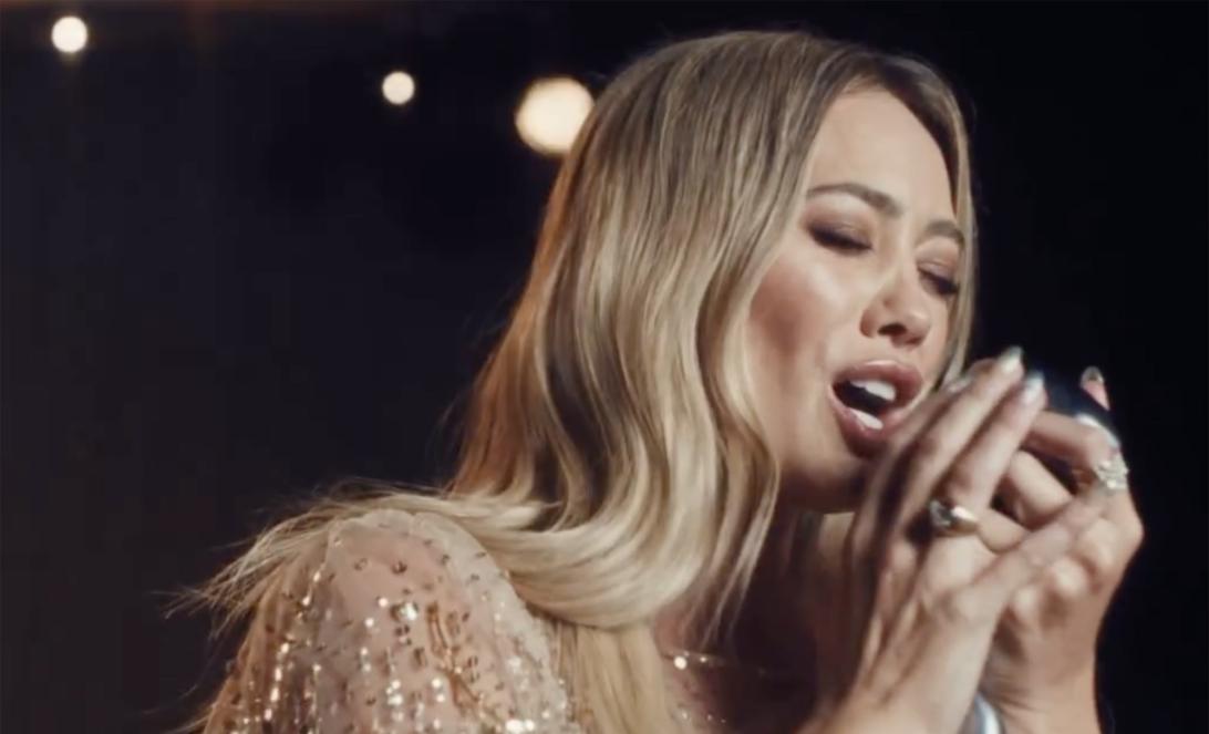 Хилари Дафф исполняет песню в микрофон.