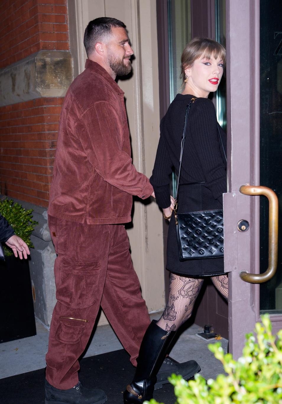Трэвис Келси и Тейлор Свифт покидают здание, держась за руки.