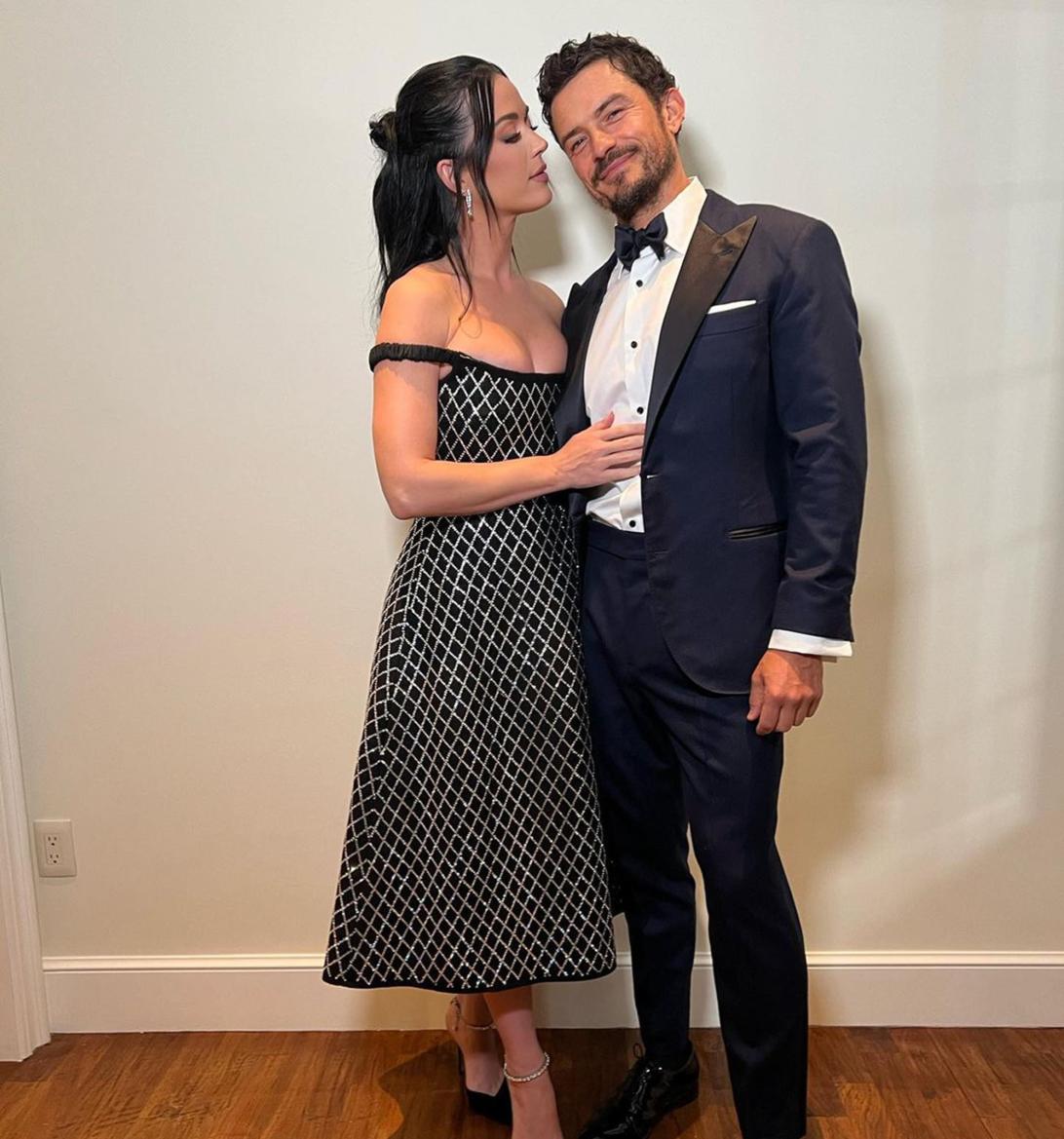 Кэти Перри и Орландо Блум улыбаются, позируя для снимка, Перри обнимает Блума.