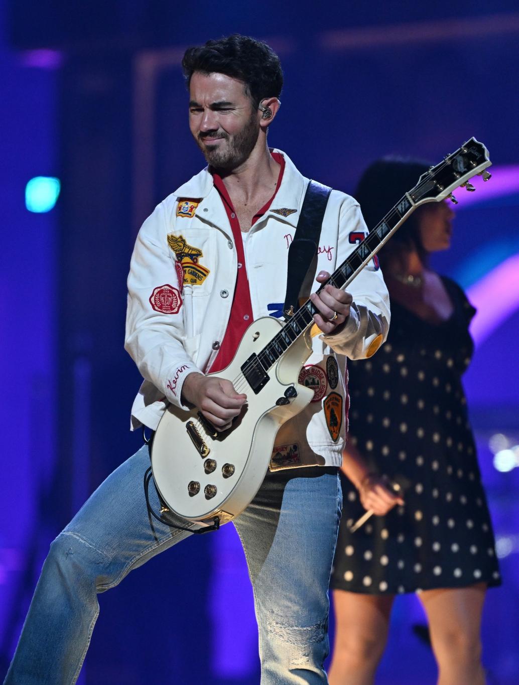 Кевин Джонас зажигает на сцене, играя на электрогитаре.