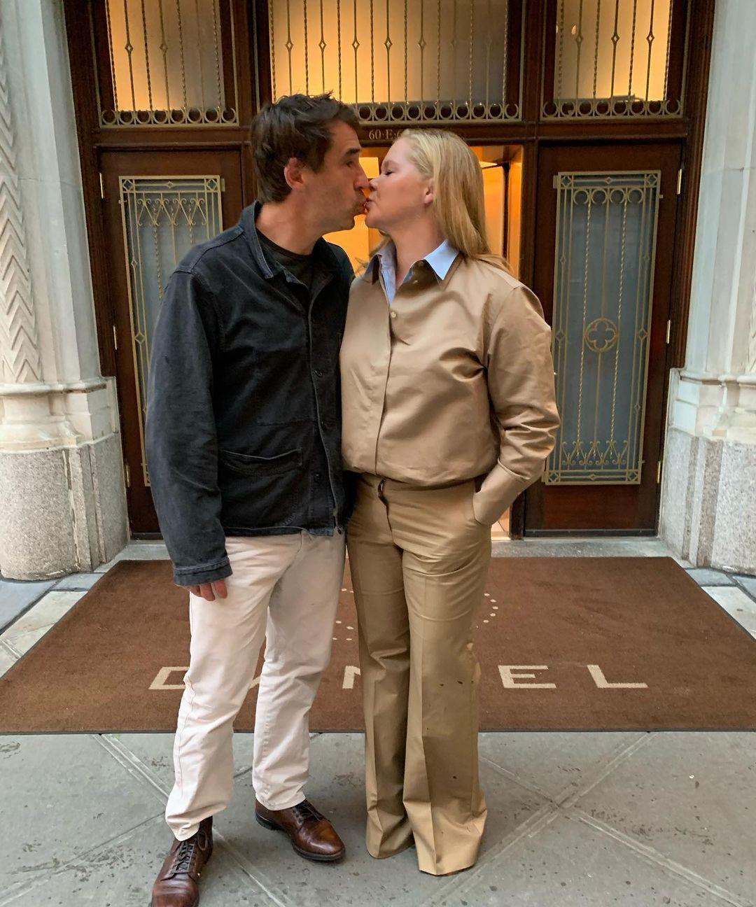 Эми Шумер целуется с мужчиной у здания.