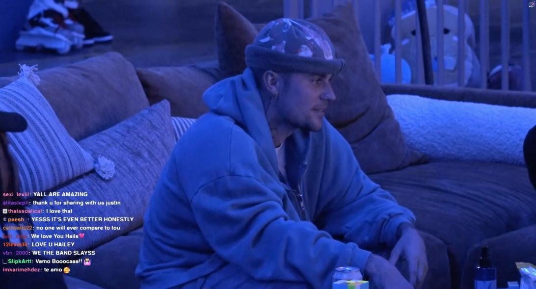 Джастин Бибер в шапке-бини и синей толстовке на диване.