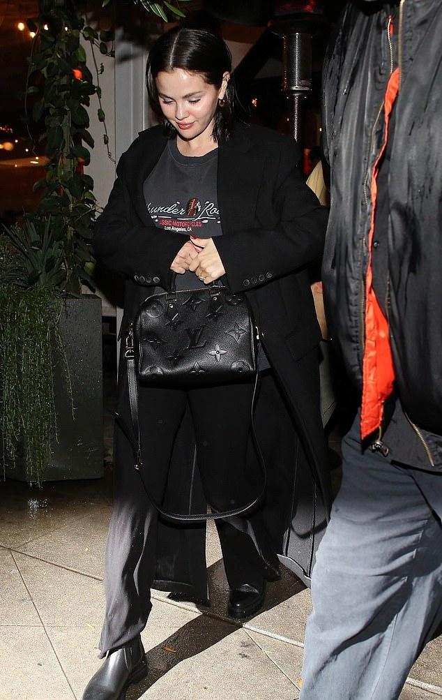 Селена закуталась в длинное черное пальто, под которым были темно-серый джемпер с круглым вырезом и черные брюки.