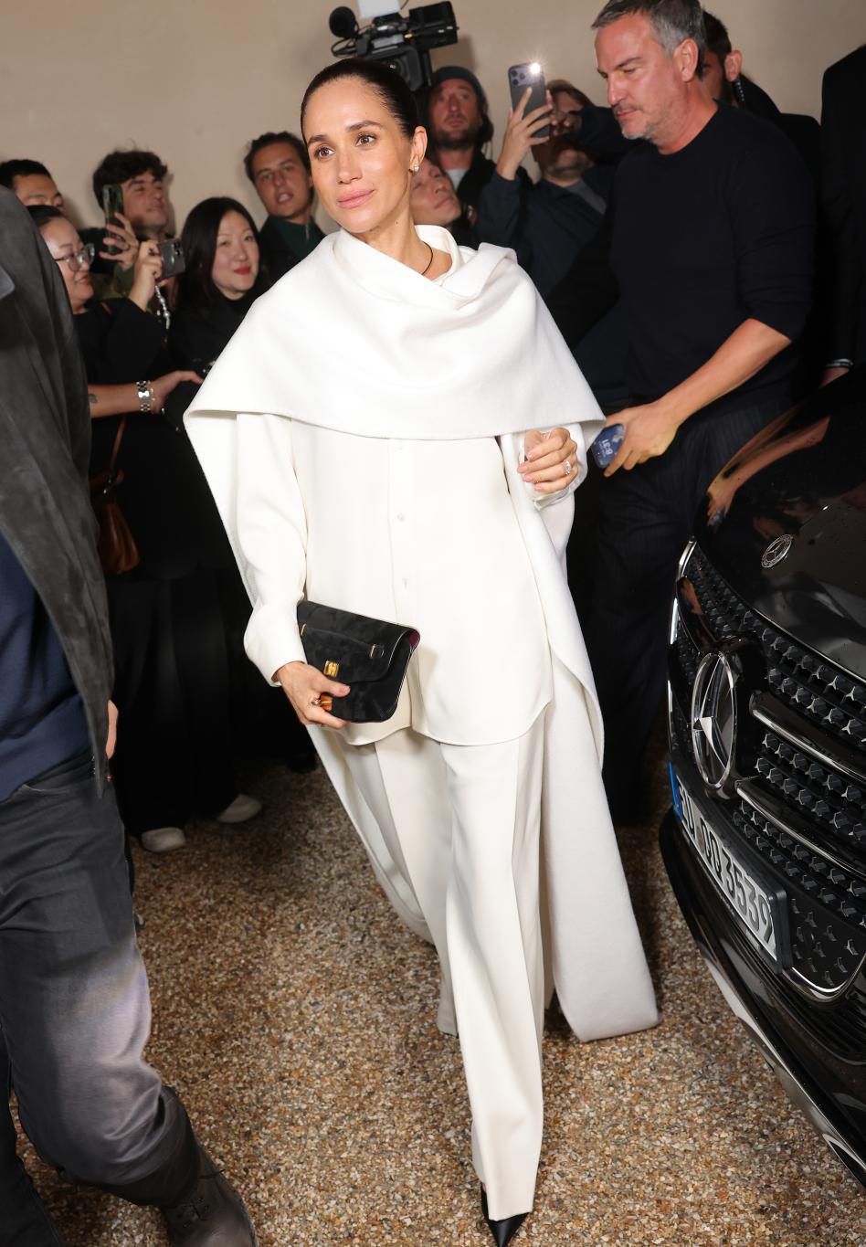 На Неделе моды в Париже Меган Маркл появилась в белоснежном наряде с черным клатчем, привлекая взгляды на фоне городской суеты и машин.