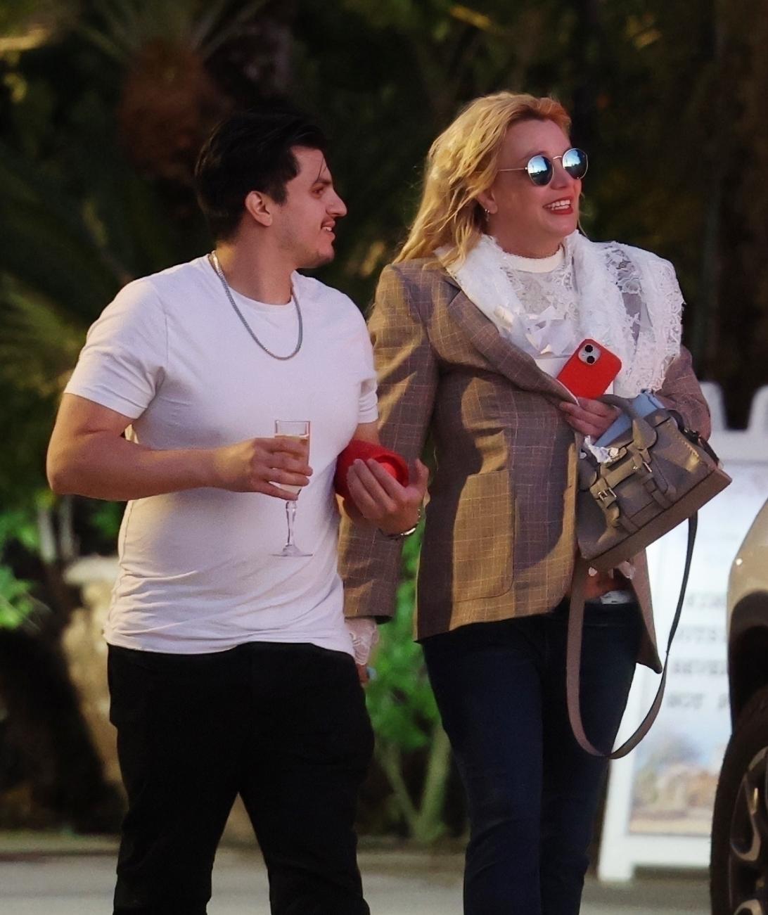 Бритни Спирс улыбается рядом с сотрудником с бокалом шампанского.