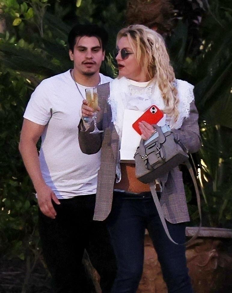 Бритни Спирс с мужчиной, с бокалом шампанского и красным телефоном в руках.