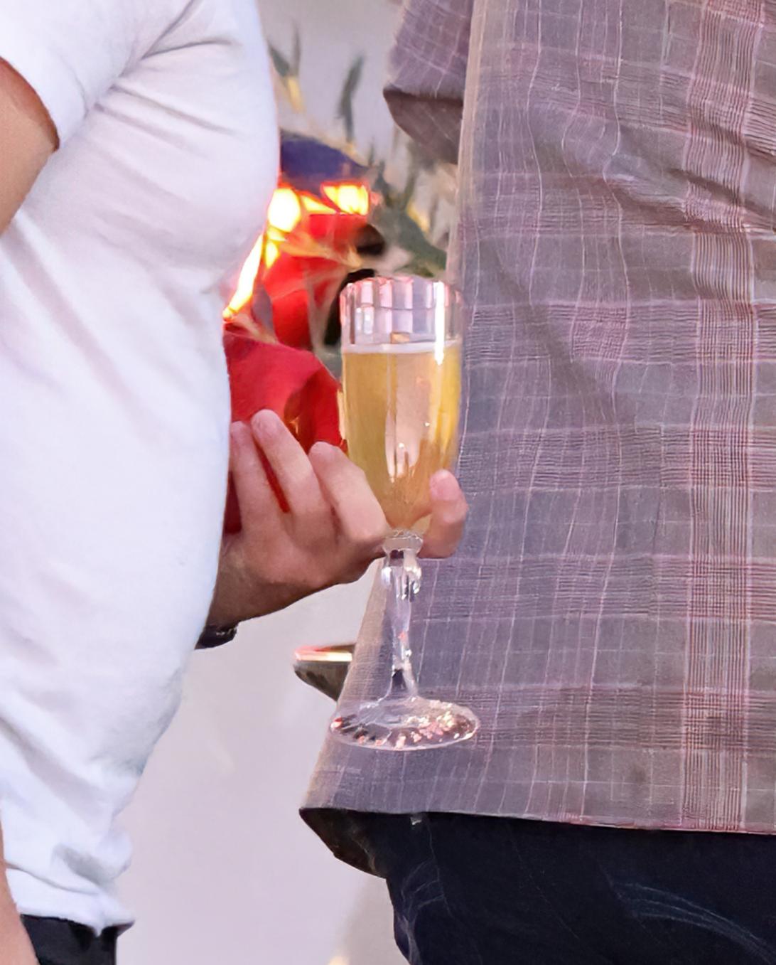 Рука, держащая бокал для шампанского с золотистым напитком.