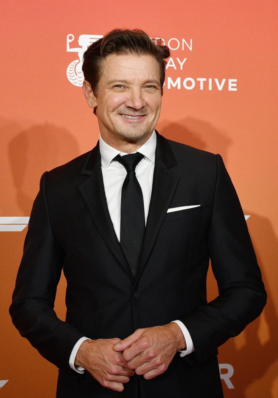 Джереми Реннер в элегантном чёрном костюме.