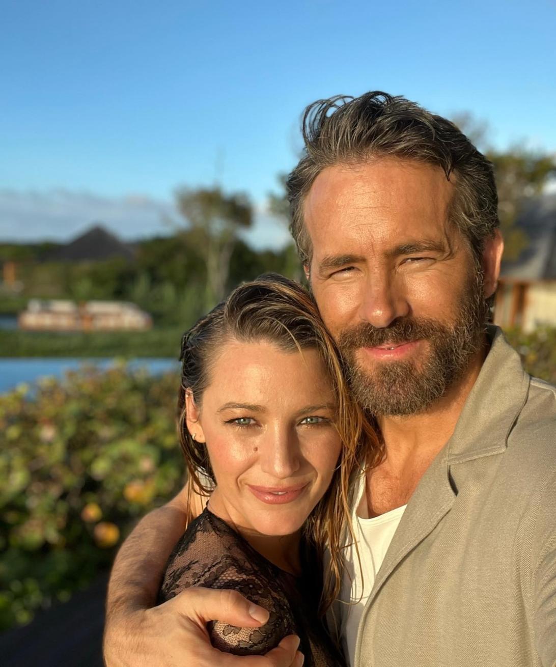 Блейк Лайвли и Райан Рейнольдс нежно обнимаются под синим небом у воды.