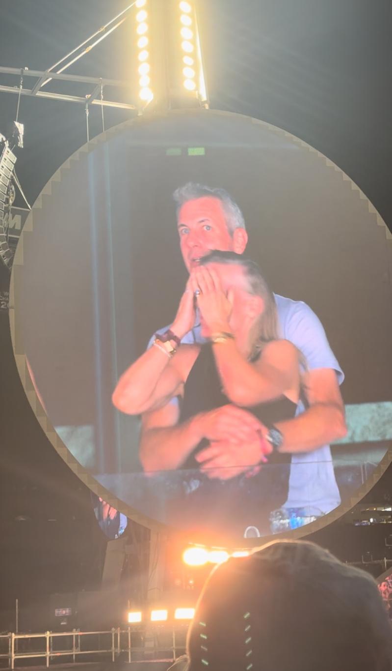 Энди Байрон и Кристин Кэбот обнимаются на концерте Coldplay.