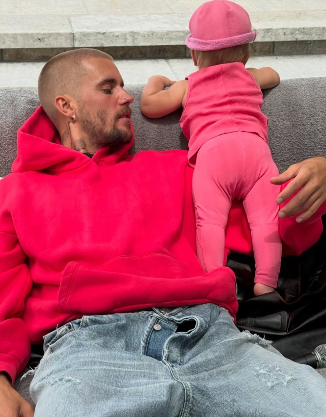 Джастин Бибер любуется малышом Джеком в розовом костюмчике и шапочке.