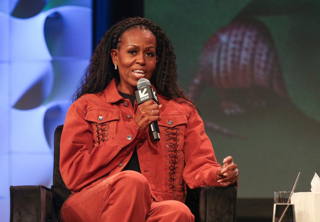 Мишель Обама уверенно обращается к аудитории, произнося речь в микрофон.