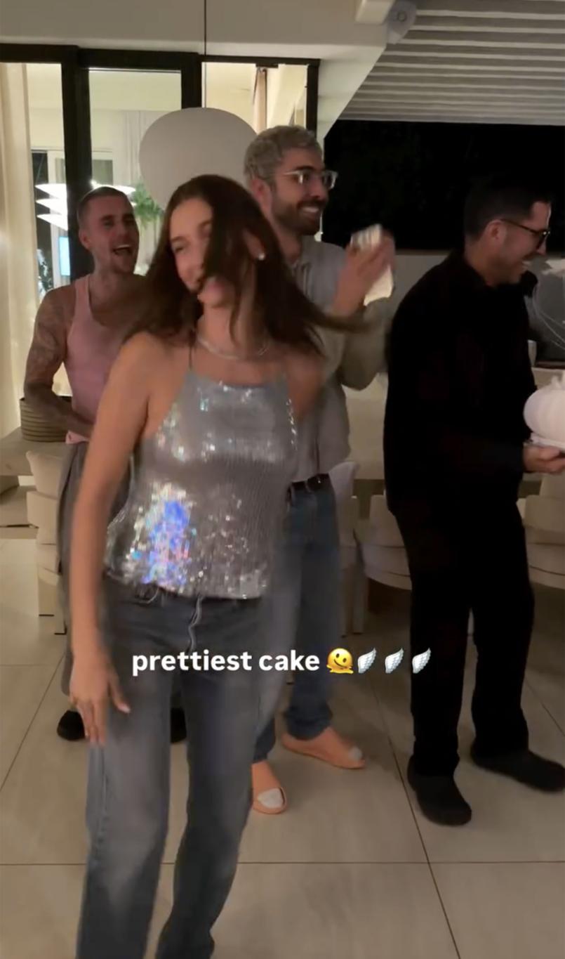 Хейли Бибер в топе с пайетками и джинсах танцует с Джастином Бибером и двумя другими мужчинами.