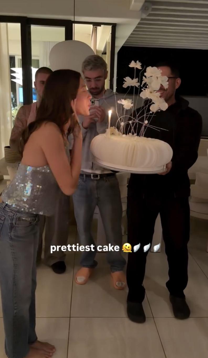 Хейли Бибер задувает свечи на именинном торте, Джастин Бибер нежно смотрит.