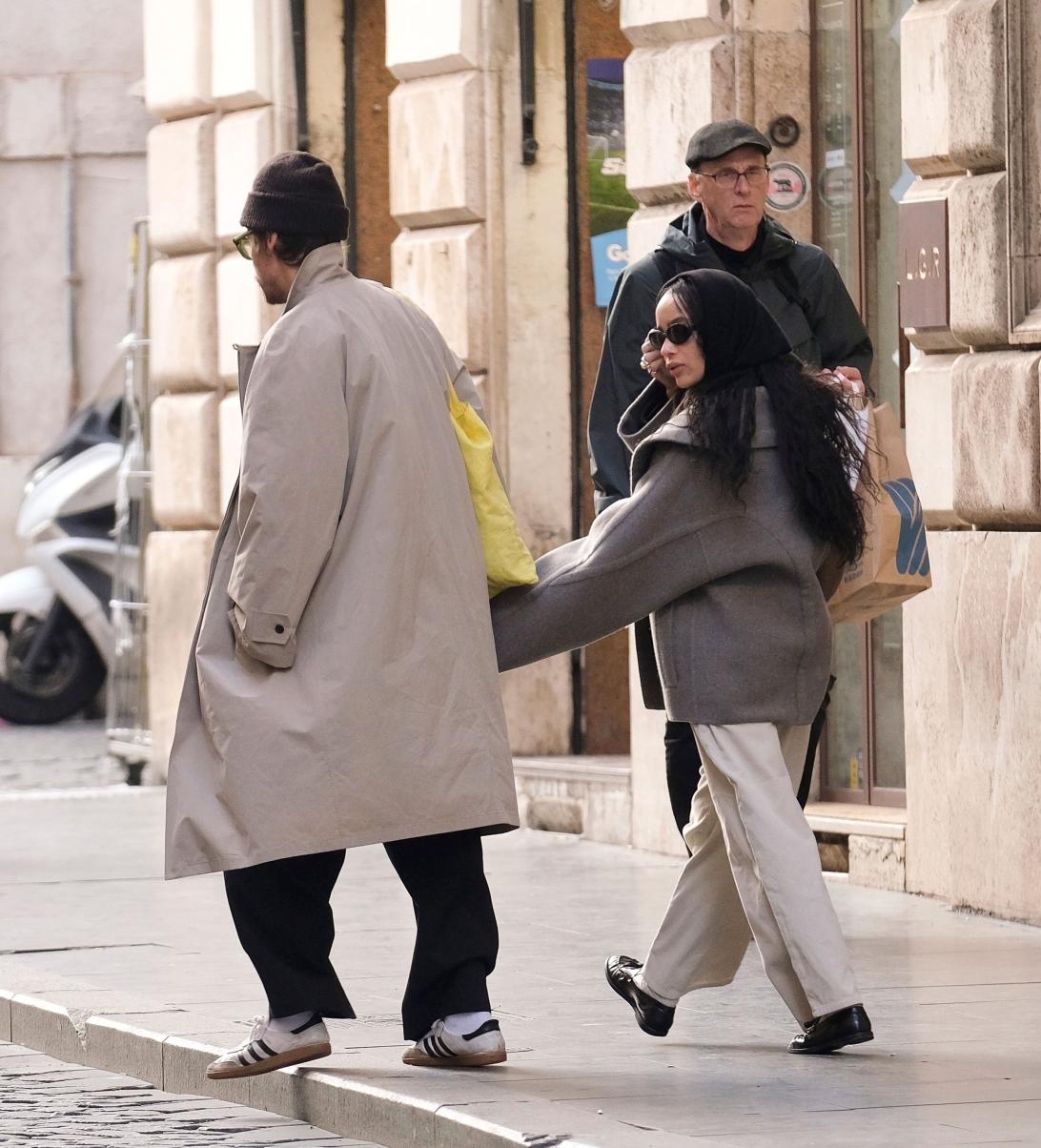 Гарри Стайлс и Зои Кравиц прогуливаются по римской улице. Гарри в бежевом тренче, Зои в сером пальто.