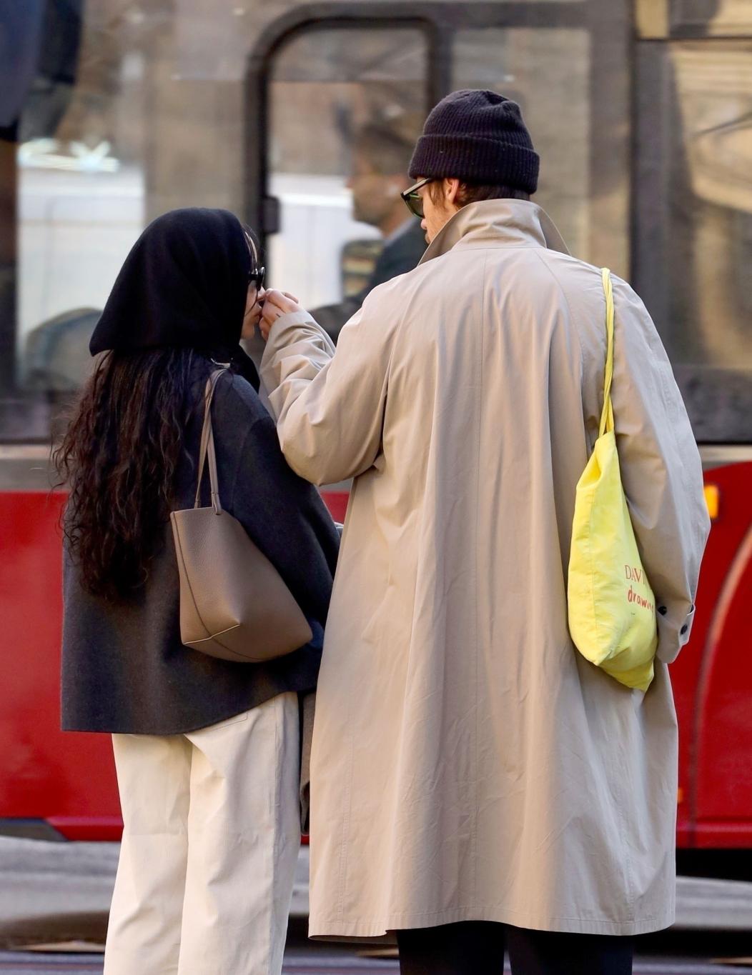 Гарри Стайлс в бежевом тренче и Зои Кравиц в черном пальто с капюшоном, рука об руку совершают покупки в Риме.