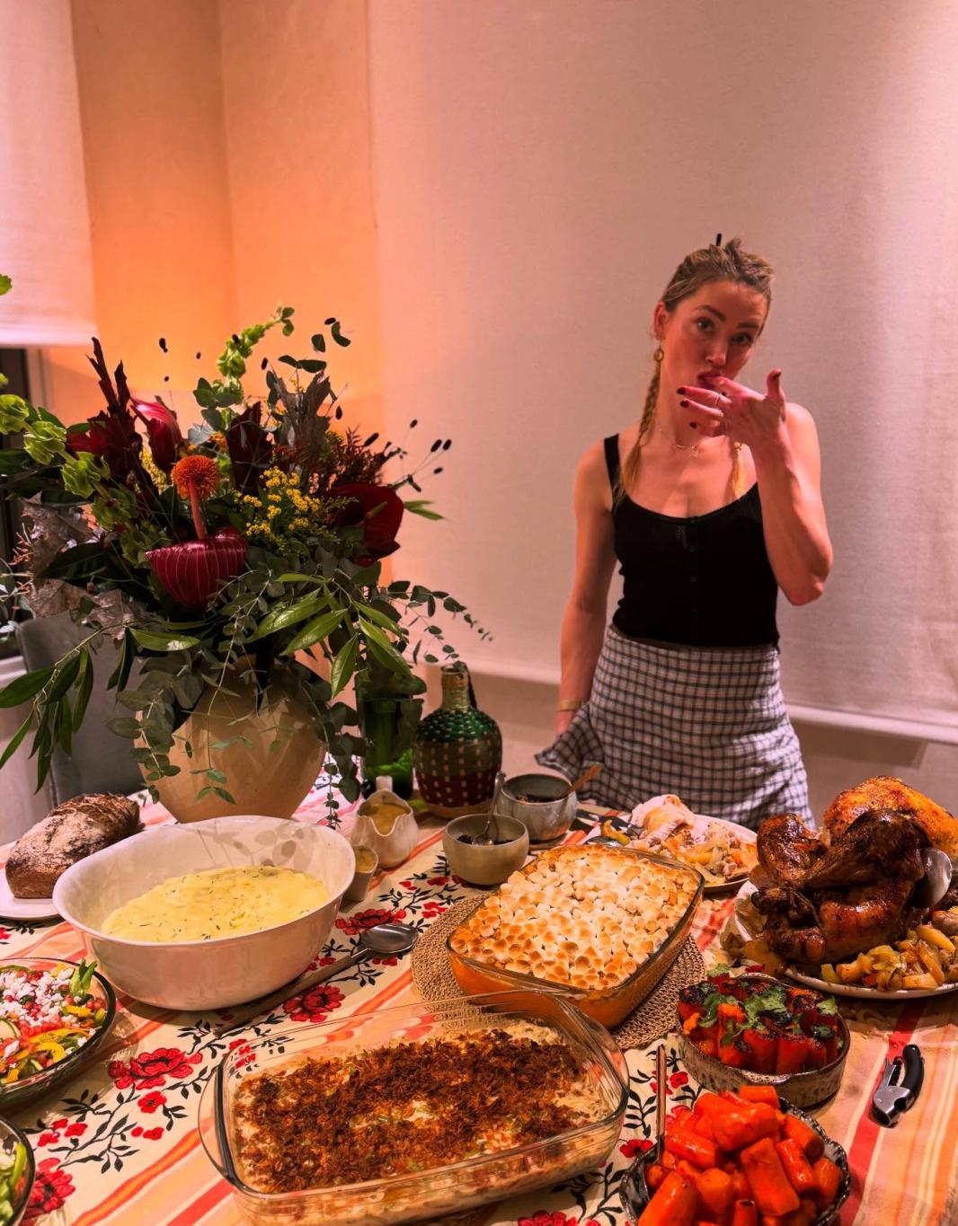 Эмбер Херд позирует за праздничным столом Дня Благодарения, ломящимся от яств.