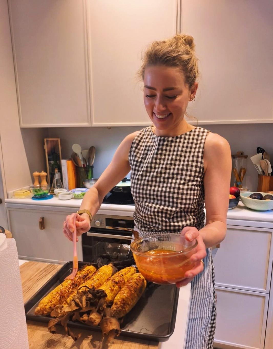 Эмбер Херд смазывает сочной заправкой обжаренные на гриле кукурузу и грибы на противне.