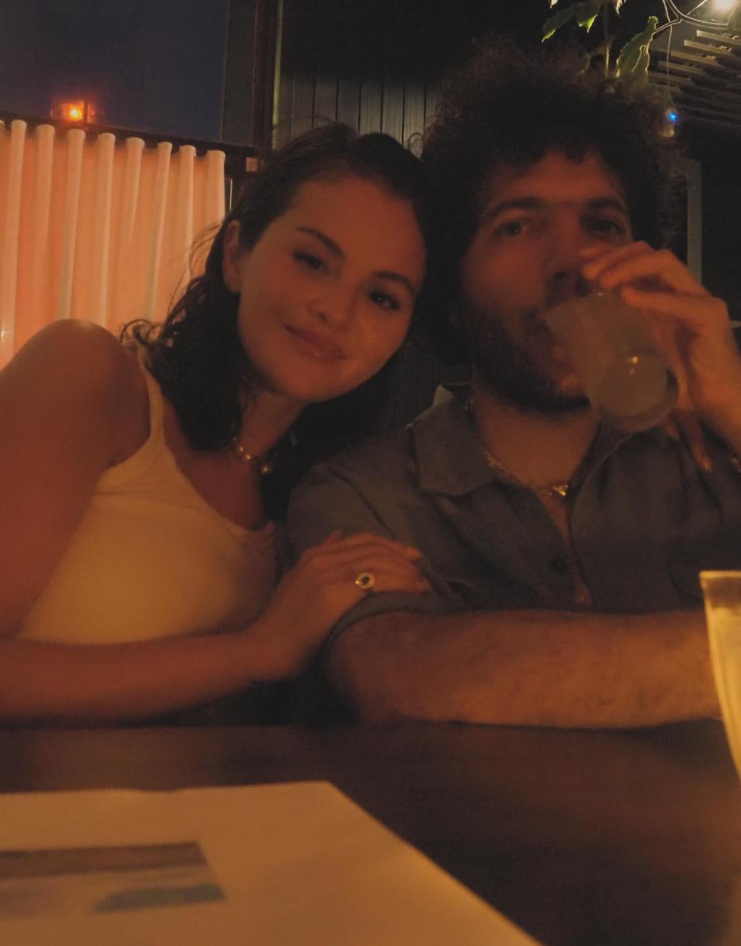 Селена Гомес с кудрявым бородатым мужчиной, пьющим из стакана.