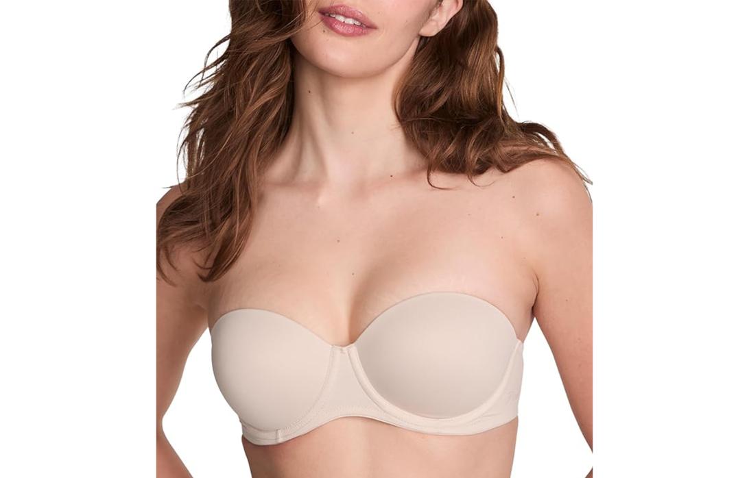 Женщина позирует в телесном бюстгальтере без бретелек.