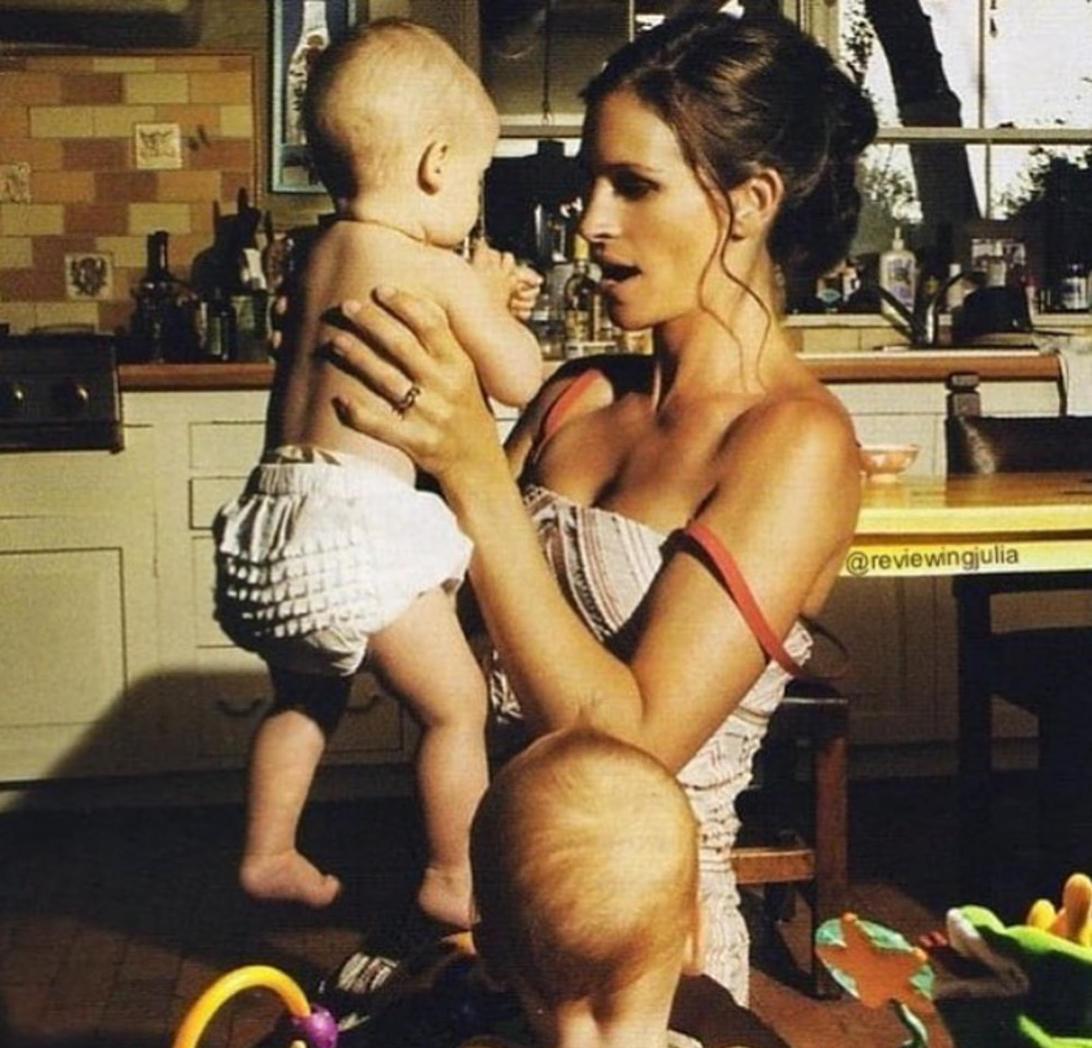 Джулия Робертс держит одного из своих близнецов, пока второй сидит на полу.