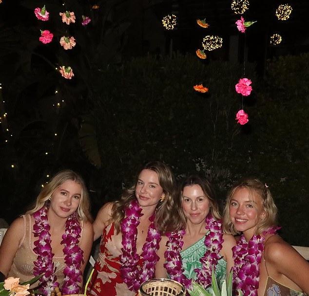 Актриса запечатлела ужин у океана: она и подруги в фиолетовых леях у стола при свечах, украшенного тропическими цветами.