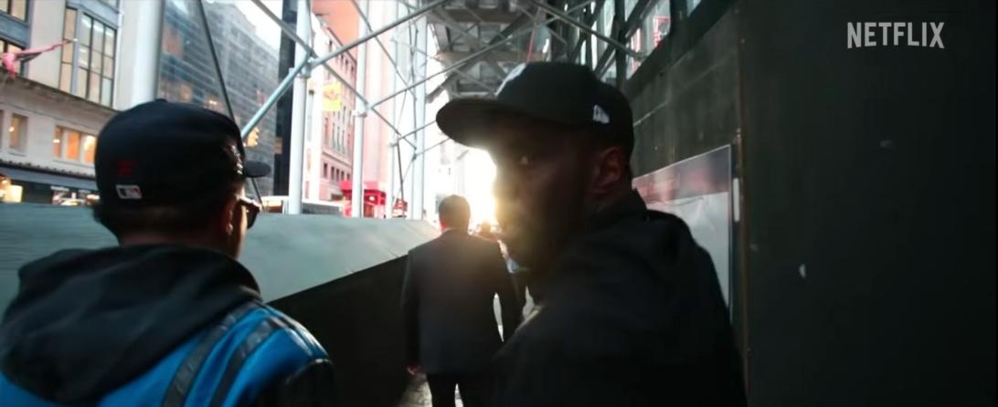 Шон "Дидди" Комбс в черной кепке конфликтует с кем-то на людной городской улице.