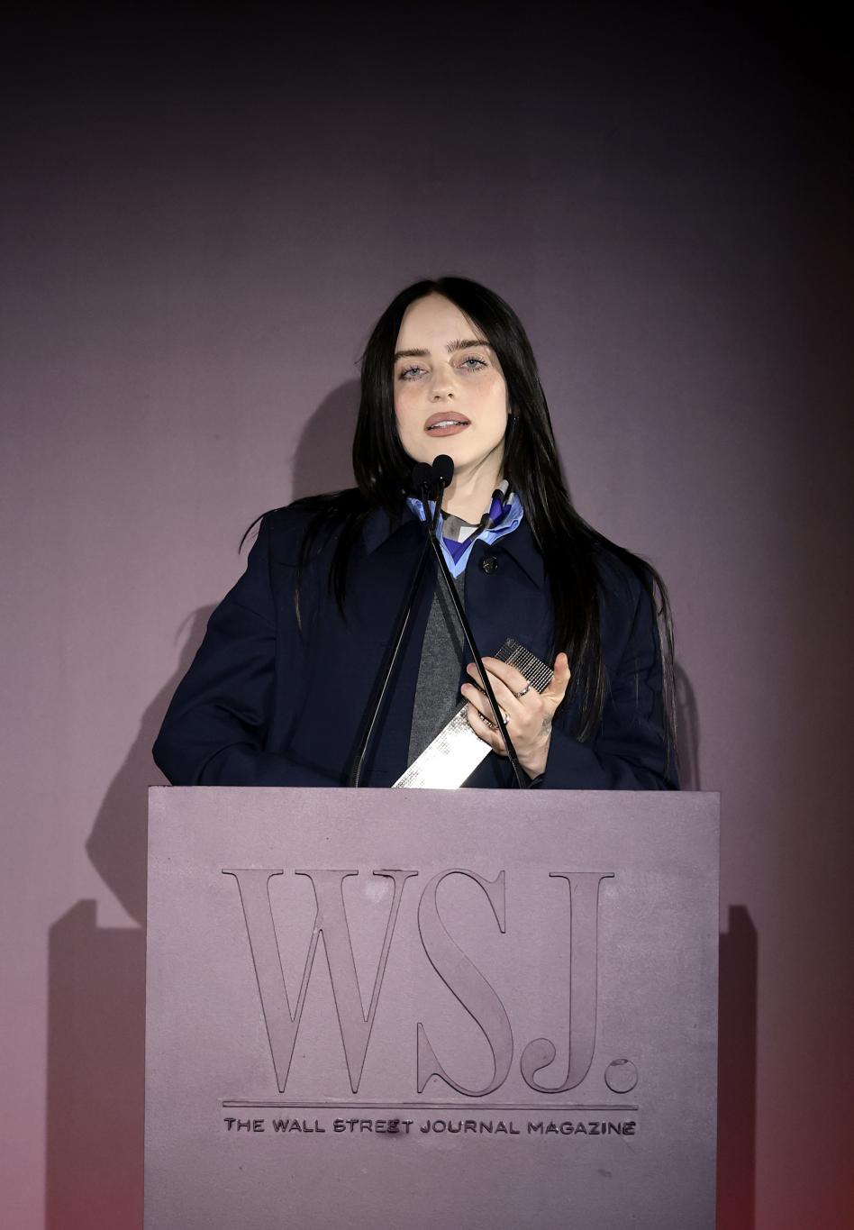 Выступление Билли Айлиш с микрофоном за трибуной на церемонии WSJ. Magazine Innovator Awards 2025.