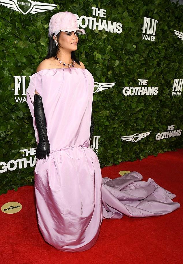 Она дополнила образ чёрными оперными перчатками из искусственной кожи и высокой шляпой, украшенной нежно-розовыми перьями.