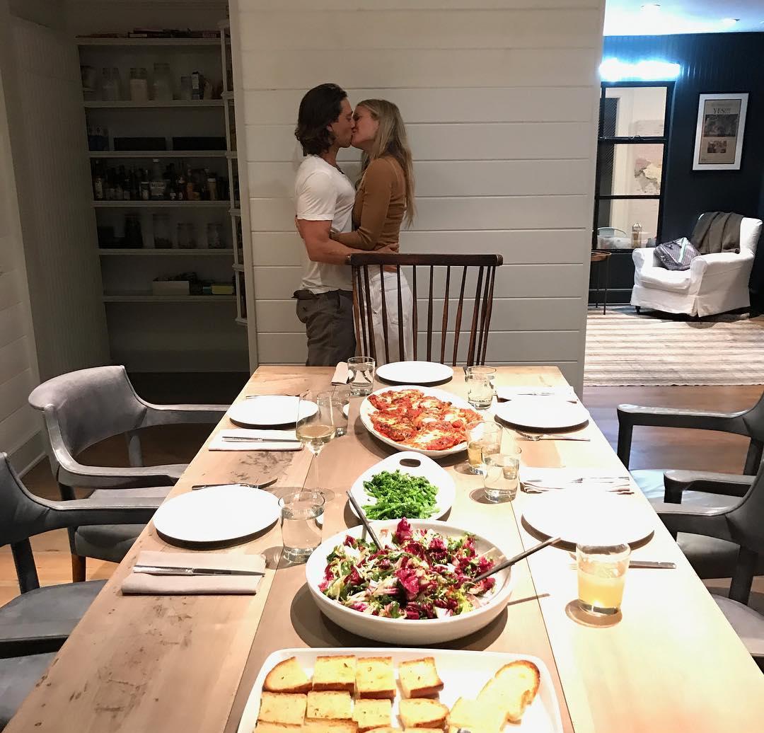 На переднем плане — накрытый обеденный стол, за которым целуются Гвинет Пэлтроу и Брэд Фэлчак.